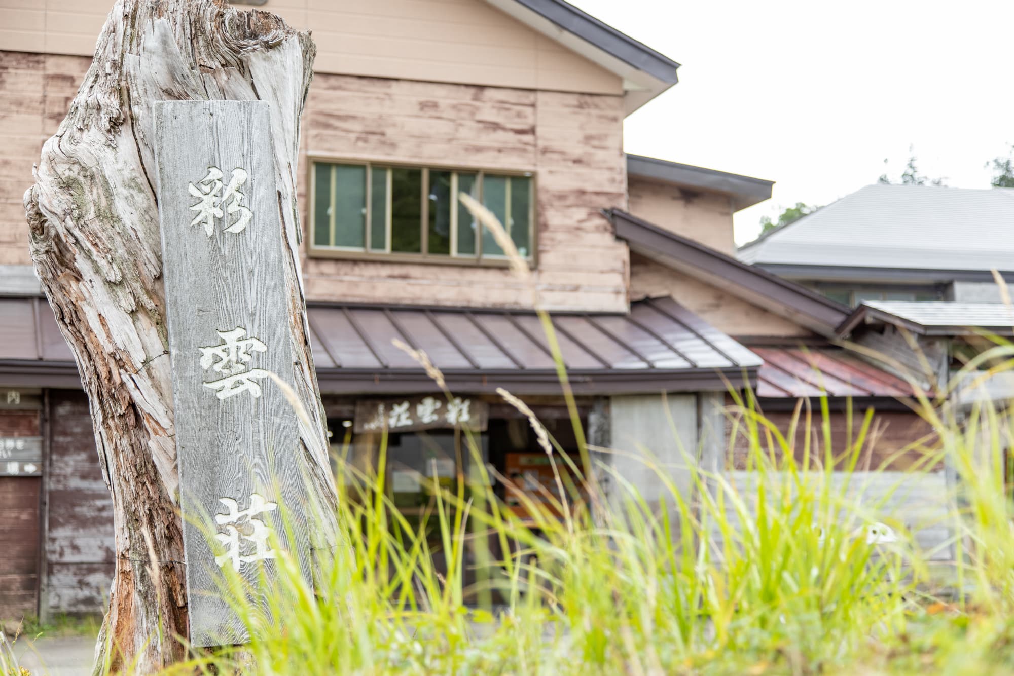 彩雲荘の木の看板と玄関